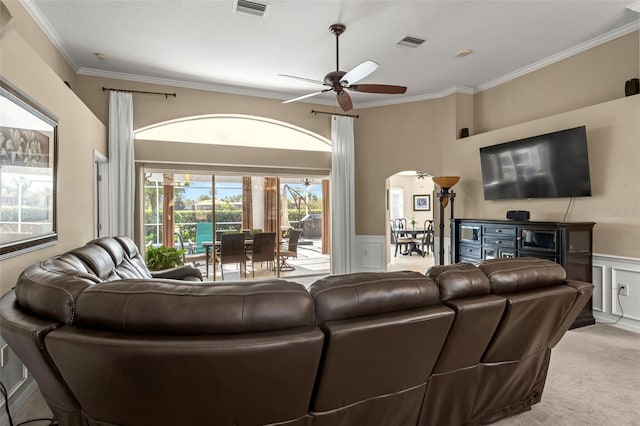 carpeted living room featuring ornamental molding, ceiling fan, and a healthy amount of sunlight