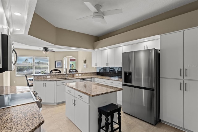 kitchen with ceiling fan, stainless steel appliances, kitchen peninsula, and a kitchen island