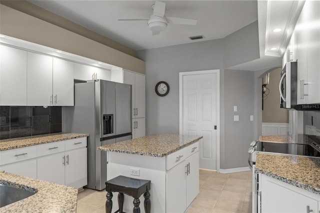 kitchen featuring ceiling fan, tasteful backsplash, a kitchen island, white cabinetry, and appliances with stainless steel finishes