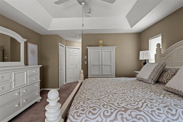 bedroom featuring dark colored carpet, ceiling fan, and a tray ceiling