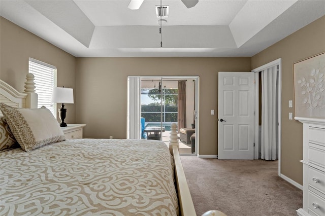 bedroom with ceiling fan, a tray ceiling, access to exterior, and multiple windows