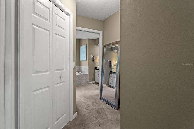 hallway with light colored carpet and a textured ceiling