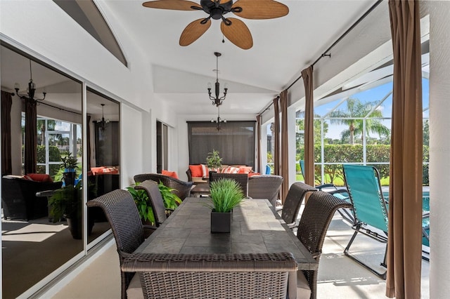 sunroom / solarium with ceiling fan with notable chandelier, vaulted ceiling, and a healthy amount of sunlight