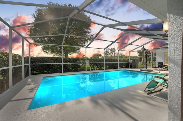 pool at dusk featuring a lanai and a patio area