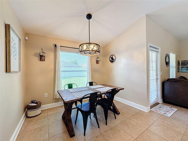 tiled dining area with a textured ceiling and an inviting chandelier