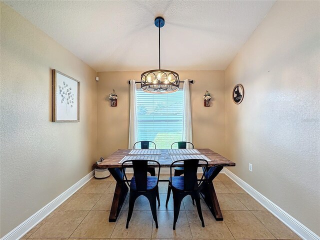 dining area featuring light tile patterned flooring, a textured ceiling, and an inviting chandelier