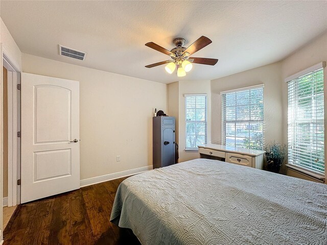 bedroom with ceiling fan, dark hardwood / wood-style flooring, and a textured ceiling