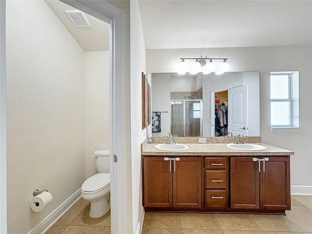 bathroom with tile patterned floors, vanity, toilet, and walk in shower