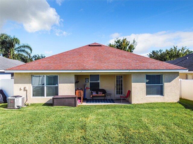 rear view of property with cooling unit, a patio area, and a lawn