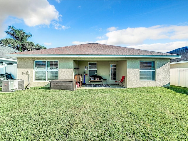 back of property with a lawn, a patio, and central AC