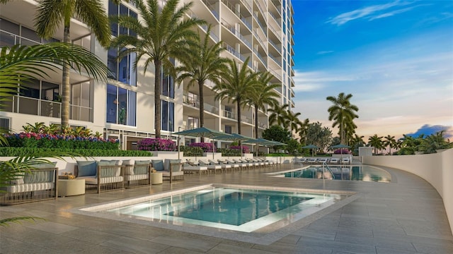 pool at dusk featuring outdoor lounge area and a patio area