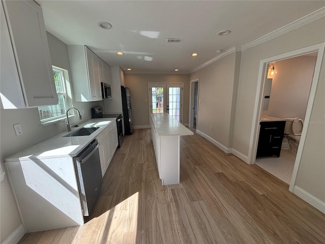 kitchen featuring appliances with stainless steel finishes, white cabinetry, a center island, and sink