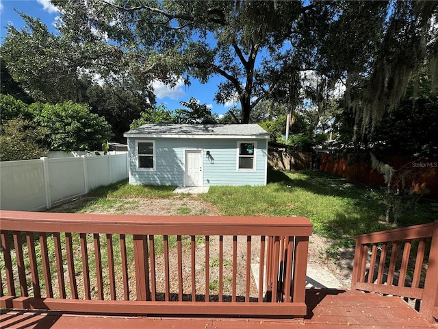 rear view of property featuring a wooden deck, an outdoor structure, and a yard