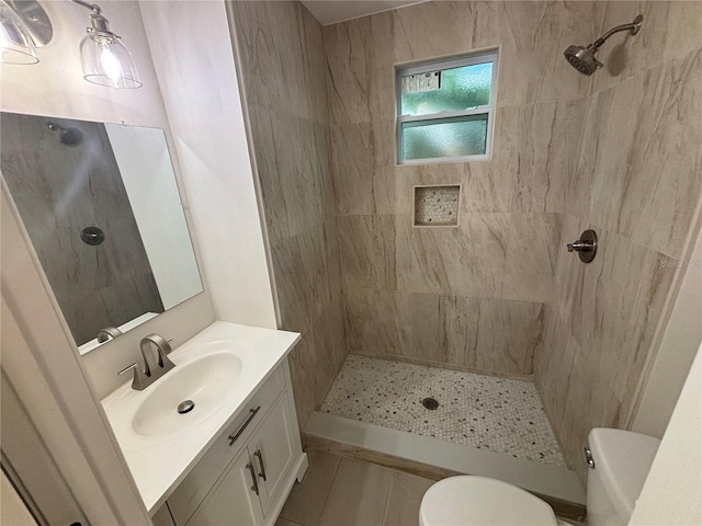 bathroom with a tile shower, vanity, toilet, and tile patterned floors