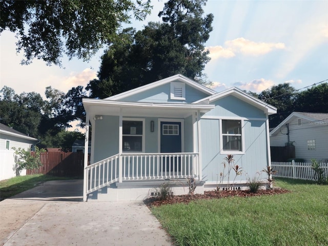 bungalow with covered porch, a front lawn, and fence