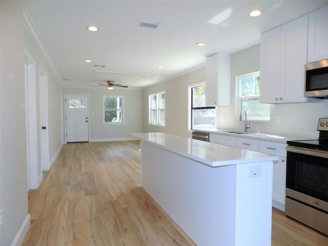 kitchen featuring a sink, crown molding, a kitchen island, and stainless steel appliances