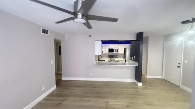 unfurnished living room featuring ceiling fan, hardwood / wood-style floors, and sink