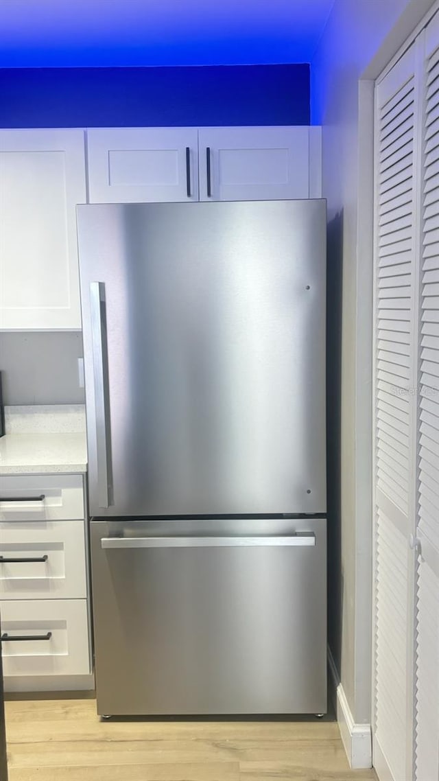 kitchen with white cabinets, stainless steel fridge, and light hardwood / wood-style floors