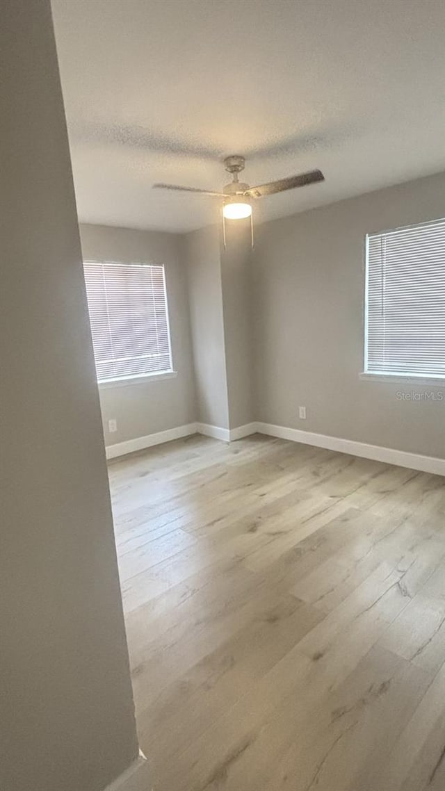 empty room with light hardwood / wood-style flooring, ceiling fan, and a textured ceiling