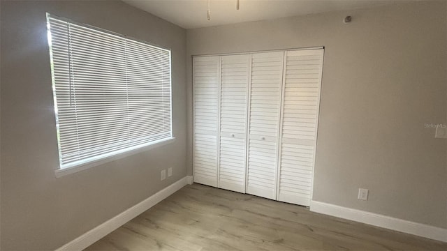 unfurnished bedroom with light hardwood / wood-style flooring and a closet