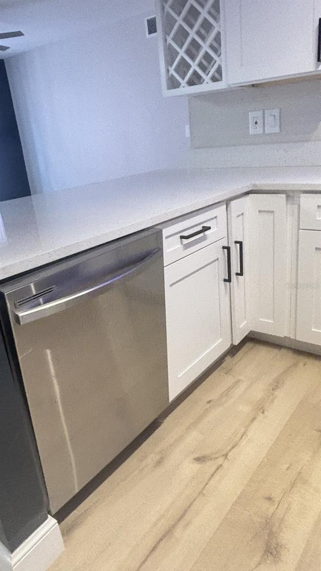 3002 W Cleveland St Unit E1, Tampa, FL 33609 - kitchen with dishwasher, light wood-style flooring, white cabinetry, and light countertops