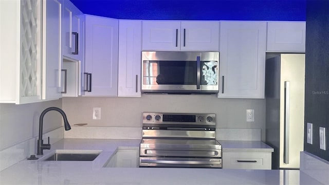 3002 W Cleveland St Unit E1, Tampa, FL 33609 - kitchen with stainless steel appliances, a sink, light countertops, and white cabinets