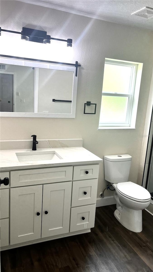 bathroom featuring wood-type flooring, a textured ceiling, toilet, and vanity