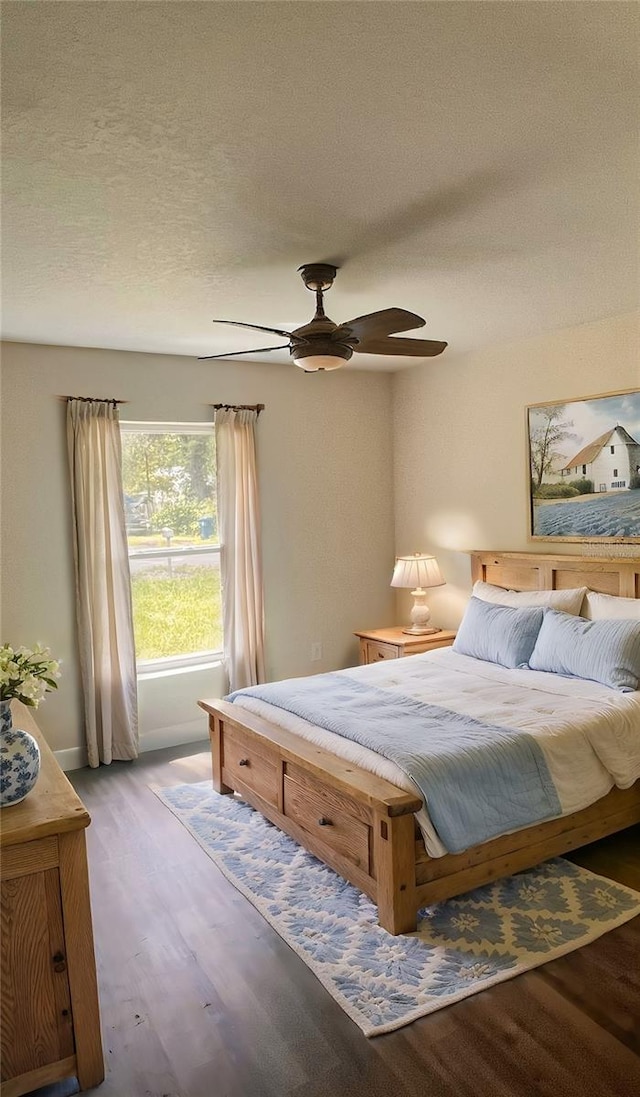 bedroom with ceiling fan, a textured ceiling, and wood-type flooring