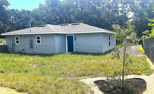 rear view of house featuring central air condition unit and a yard