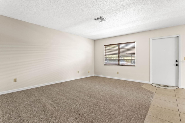 tiled spare room featuring a textured ceiling