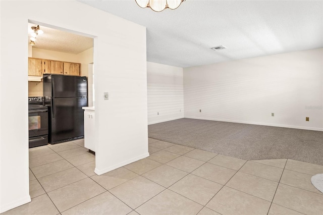 kitchen with a textured ceiling, black appliances, light brown cabinets, and light colored carpet