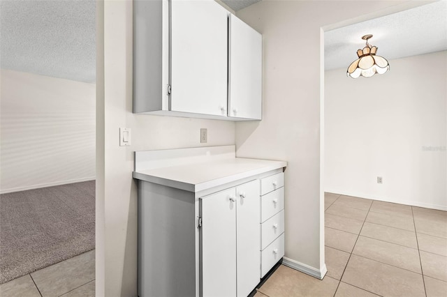 kitchen with light carpet, a textured ceiling, and white cabinetry