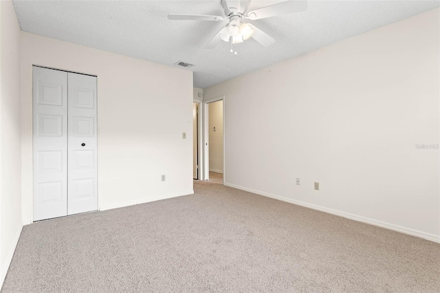 unfurnished bedroom featuring carpet flooring, a closet, ceiling fan, and a textured ceiling