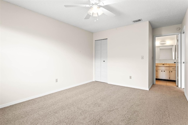 unfurnished bedroom featuring a textured ceiling, light carpet, ceiling fan, and a closet