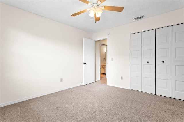 unfurnished bedroom featuring light carpet, a closet, ceiling fan, and a textured ceiling