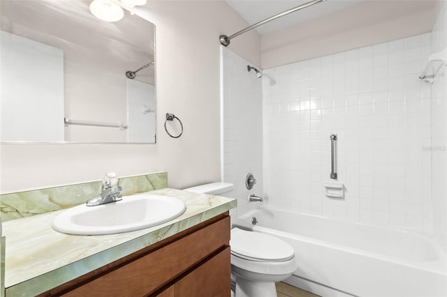 full bathroom featuring tiled shower / bath, vanity, and toilet