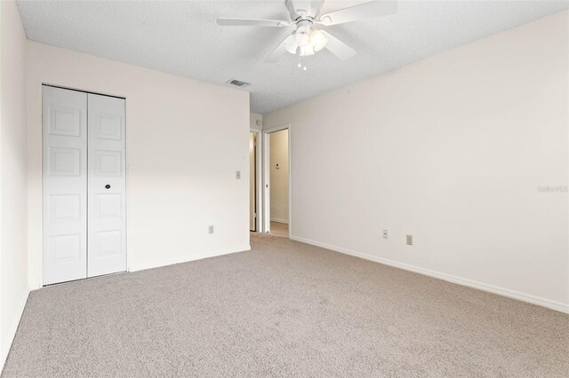 2222 Greenhaven Dr, Sun City Center, FL 33573 - unfurnished bedroom with carpet flooring, a closet, baseboards, ceiling fan, and a textured ceiling