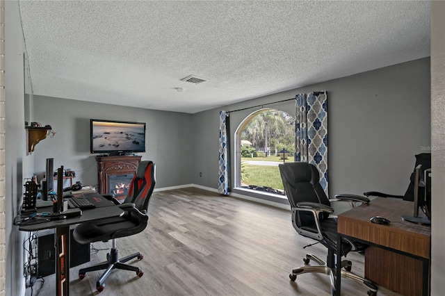 office with light wood-type flooring and a textured ceiling