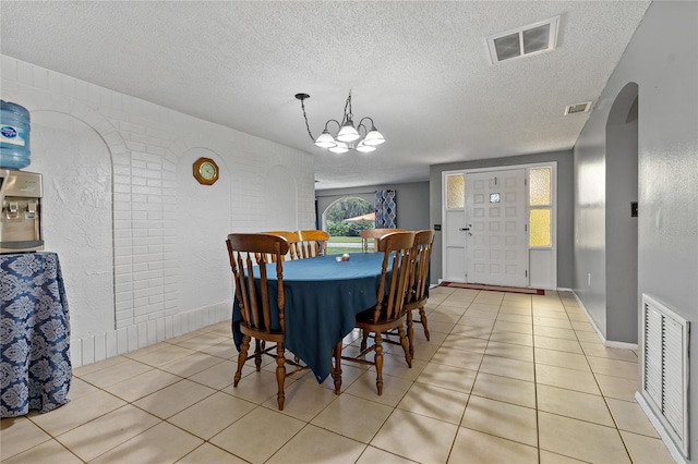 dining room featuring a notable chandelier, a textured ceiling, and light tile patterned flooring