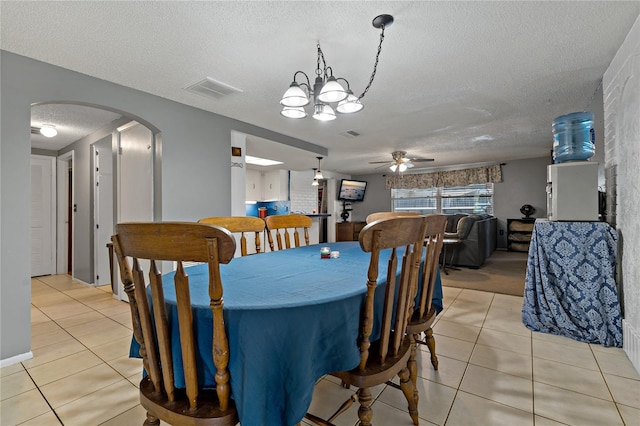 dining space with a textured ceiling, ceiling fan with notable chandelier, and light tile patterned flooring