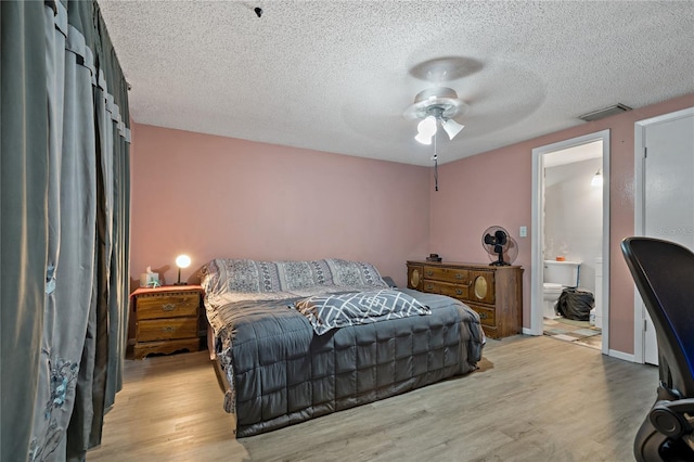 bedroom with ceiling fan, a textured ceiling, ensuite bath, and light hardwood / wood-style floors