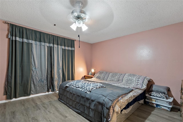 bedroom with a textured ceiling, hardwood / wood-style floors, and ceiling fan