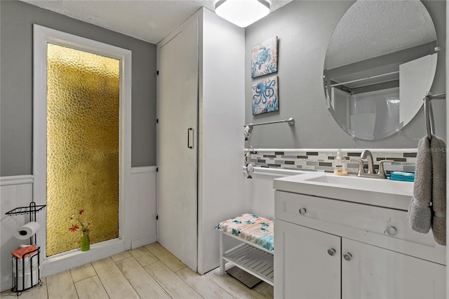 bathroom featuring vanity, backsplash, a textured ceiling, and hardwood / wood-style flooring