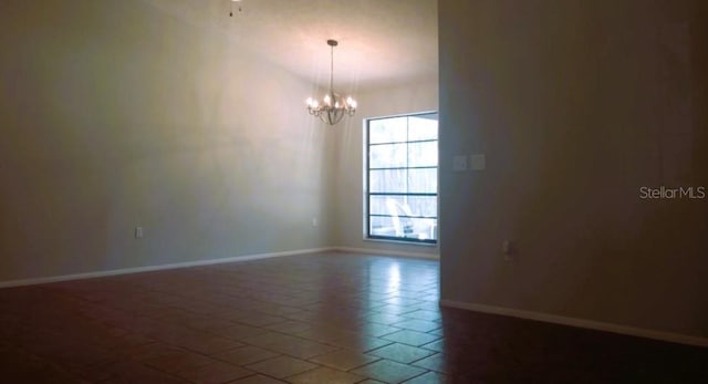 tiled spare room featuring a chandelier