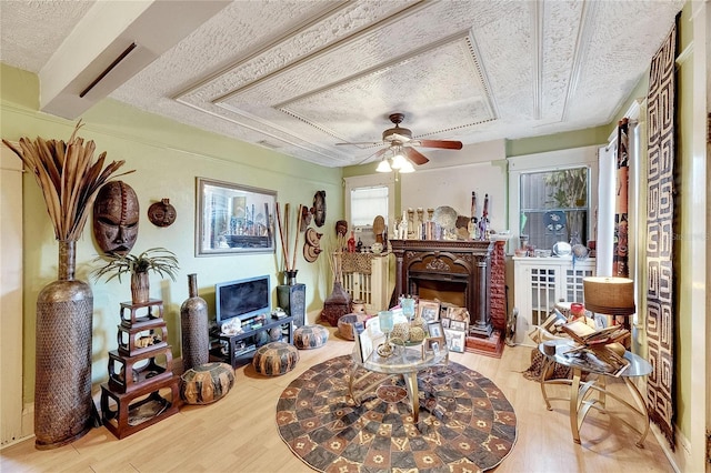 living room featuring ceiling fan, light hardwood / wood-style flooring, and a textured ceiling