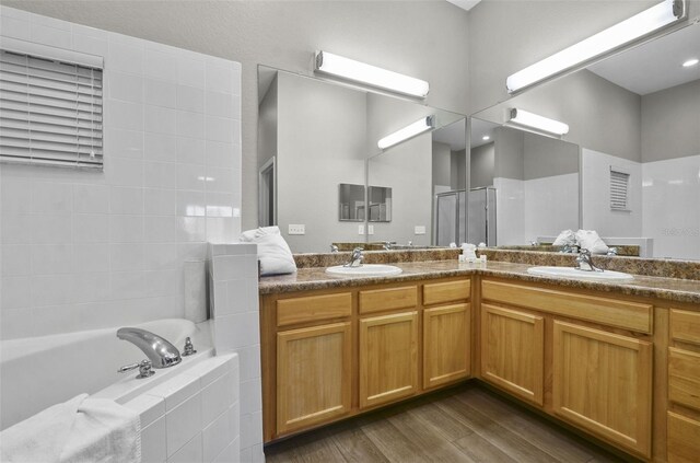 bathroom with wood-type flooring, vanity, and plus walk in shower