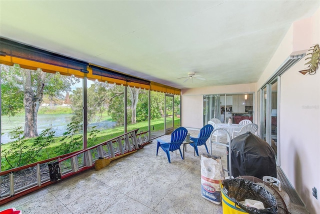 sunroom / solarium with a water view and ceiling fan