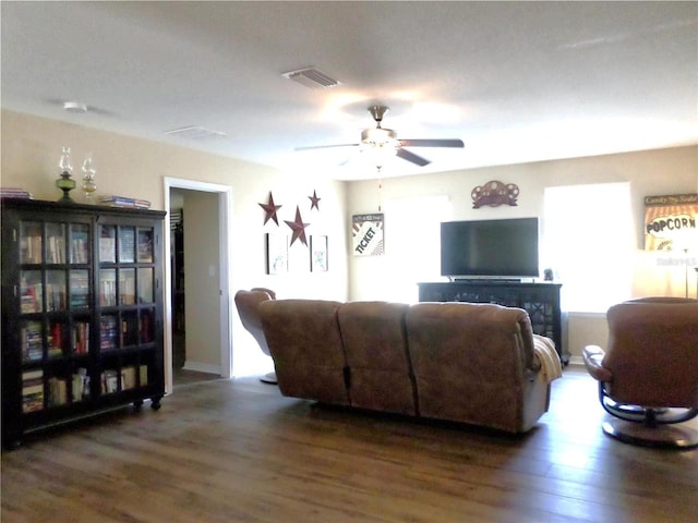 living room featuring ceiling fan and dark wood-type flooring