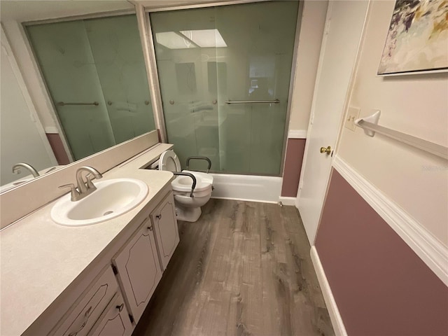 full bathroom featuring vanity, hardwood / wood-style flooring, toilet, and combined bath / shower with glass door