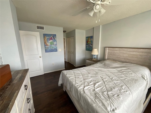 bedroom with a textured ceiling, dark hardwood / wood-style flooring, ceiling fan, and a closet